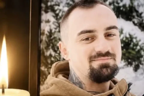 Портрет усміхненого чоловіка з бородою в рамці біля запаленої свічки