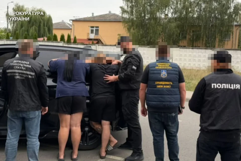 Правоохоронці затримують людей біля чорного авто на вулиці